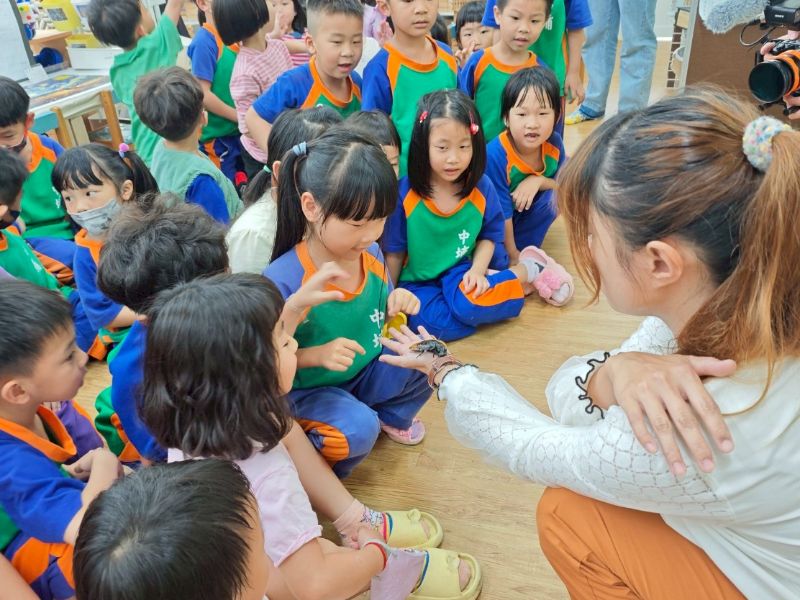 幼兒園學童在嘉大學生引導下觀察並觸摸馬達加斯加蟑螂。(照片由主辦單位提供)