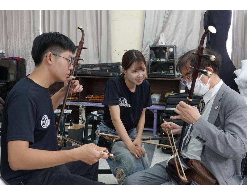 井竿富雄教授在國樂社同學的陪同下體驗樂器演奏。